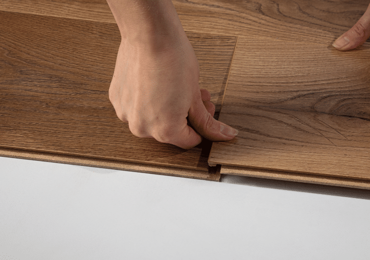 Eine Hand klickt ein Bodenpaneel in ein anderes ein