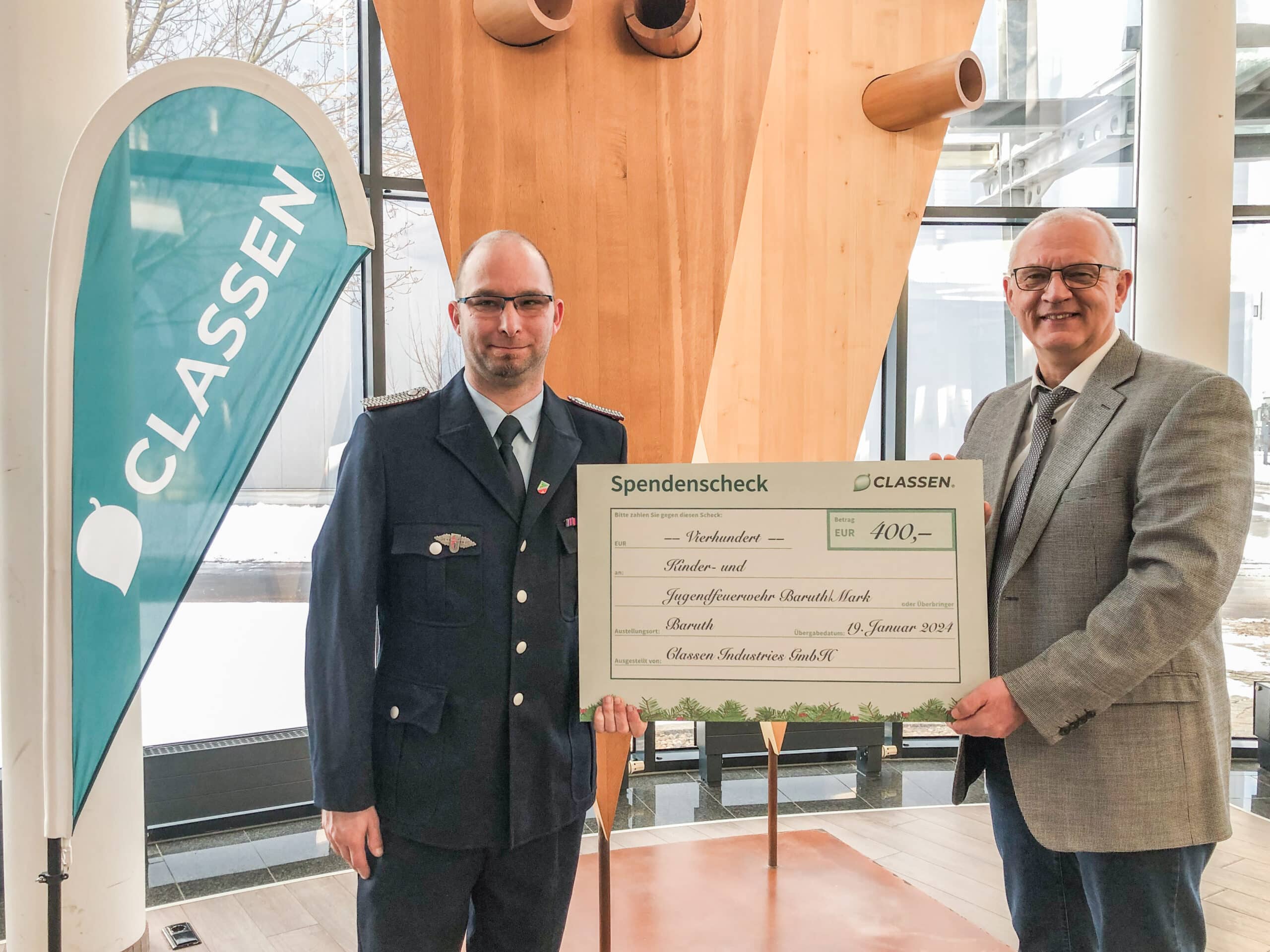 Offizielle Spendenübergabe bei CLASSEN: Zwei Männer halten einen Spendenscheck über 400 Euro für die Kinder- und Jugendfeuerwehr Baruth/Mark – Symbol für gesellschaftliches Engagement, Verantwortung und regionale Unterstützung