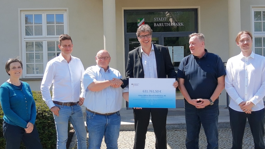 Offizielle Übergabe eines Förderbescheids über 631.761,50 Euro vor dem Rathaus Baruth/Mark: Mehrere Personen posieren gemeinsam mit Scheck – Symbol für Förderung nachhaltiger Energieprojekte und regionale Zusammenarbeit