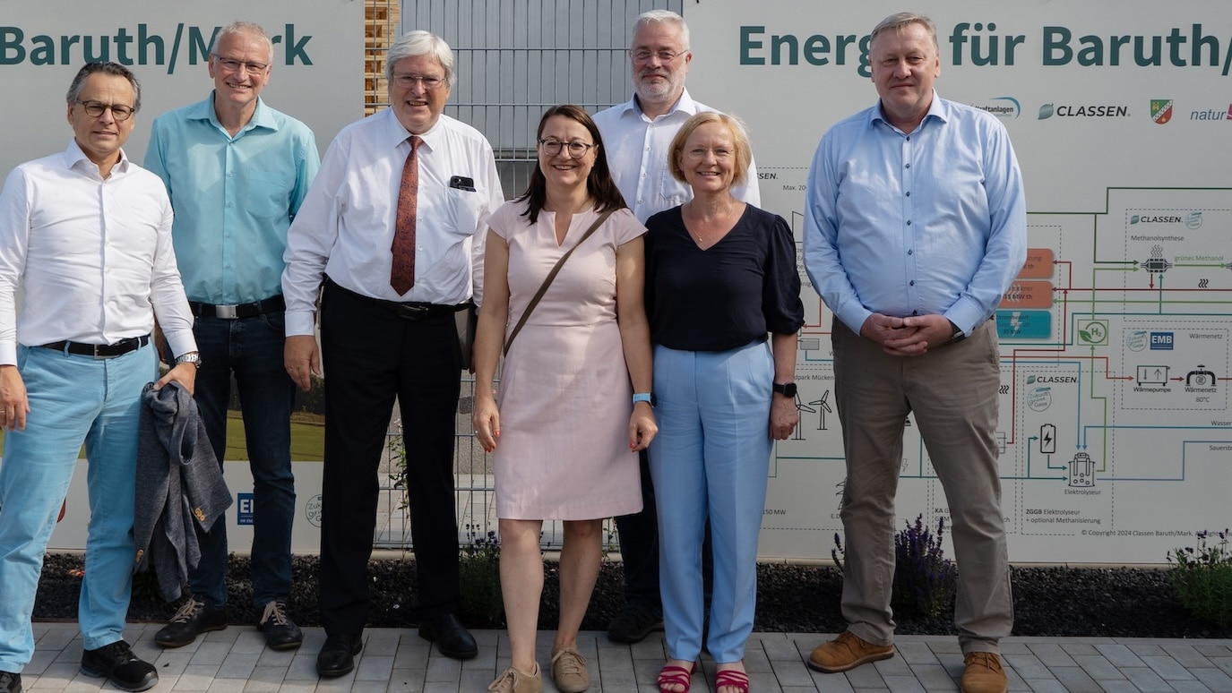 Gruppe von sieben Personen vor einer Infotafel am CLASSEN Werk Baruth/Mark, aufgenommen bei einem offiziellen Besuch – Symbol für Austausch, Zusammenarbeit und nachhaltige Energieprojekte