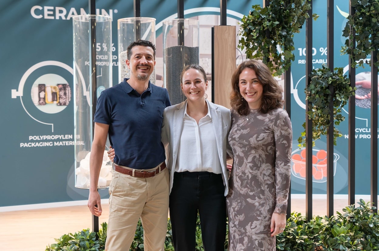 Drei Personen stehen lächelnd nebeneinander auf einer Fachmesse am CLASSEN Stand, im Hintergrund Infotafeln zu nachhaltigen Materialien und Recycling – Symbol für Innovation, Teamgeist und Umweltbewusstsein.