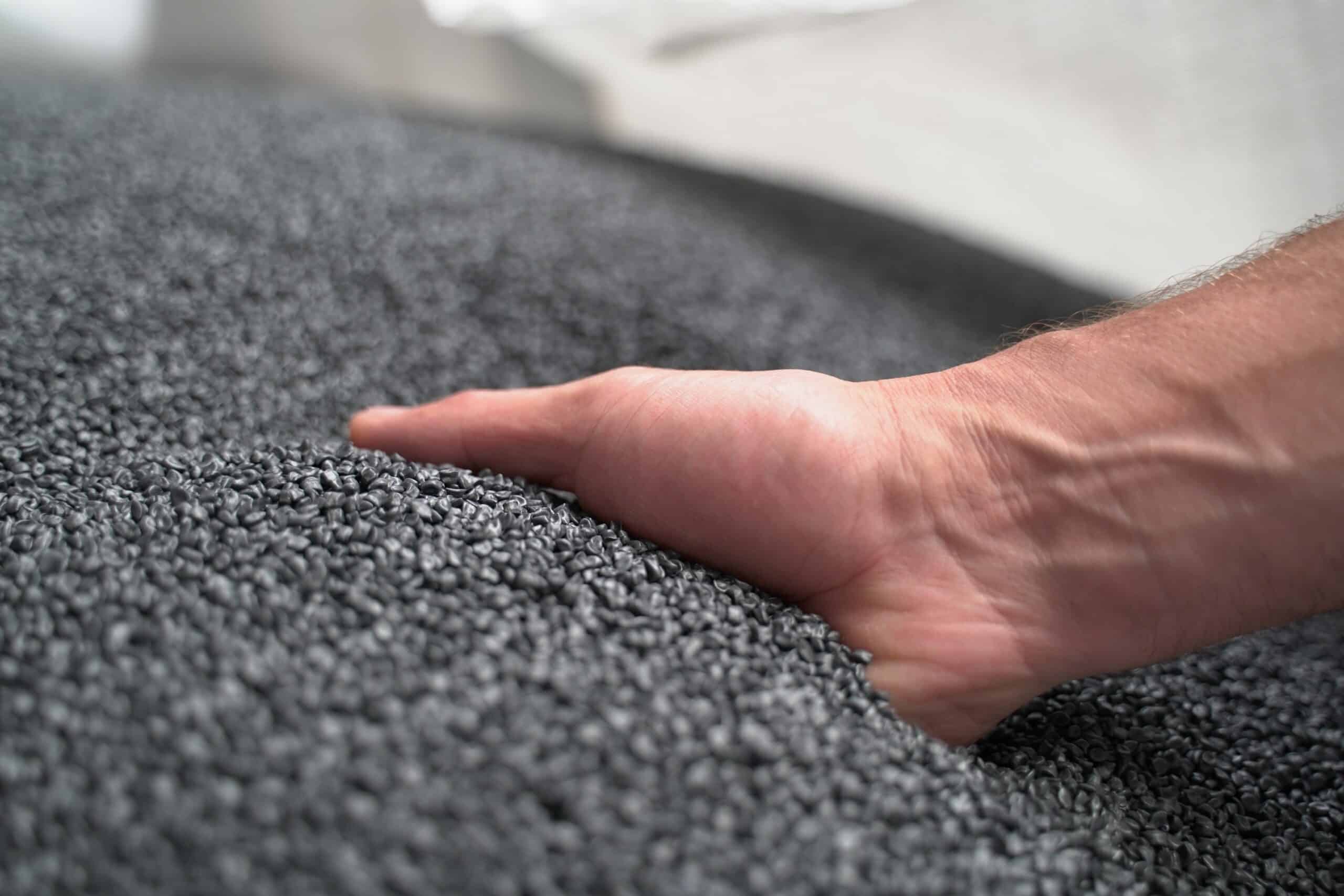 Hand greift in eine große Menge graues Ceramin®-Granulat