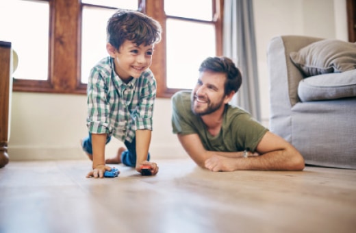 Vater und Sohn spielen gemeinsam auf einem Holzoptikboden