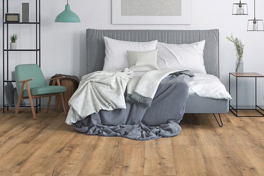 Schlafzimmer mit grauer Bettwäsche und Holzoptikboden