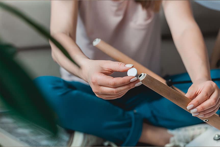 Frau bringt Filzgleiter unter Stuhl an